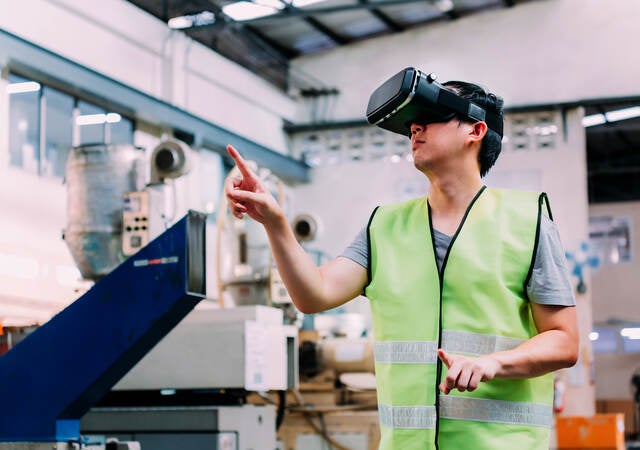 Manufacturing engineer wearing VR goggle headset in virtual reality simulation 