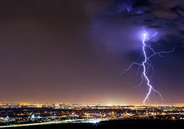 lightning striking cityscape at night 