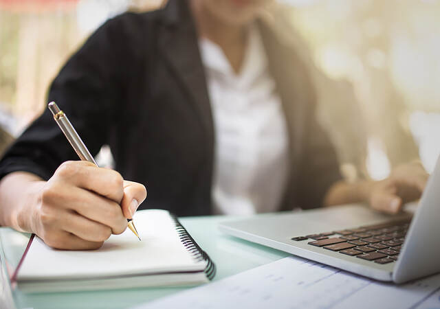 Photo of a person writing in a notebook