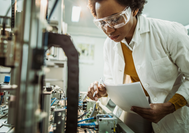 Female engineer working on industrial machine in laboratory 