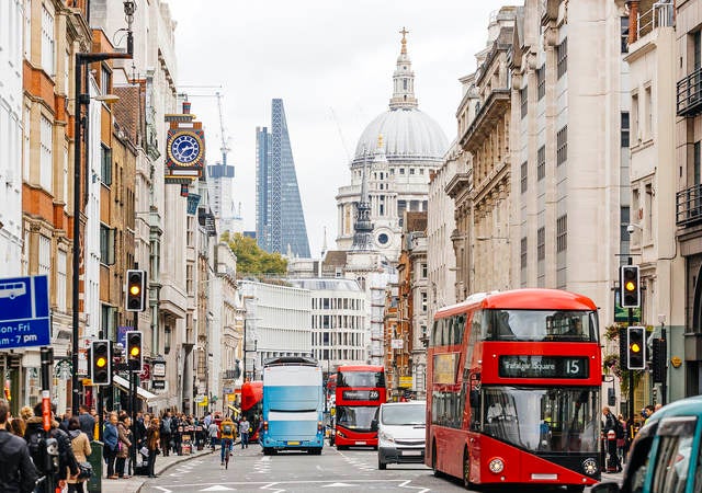 People walking on a busy street in London, England near St. Paul's Cathedral.