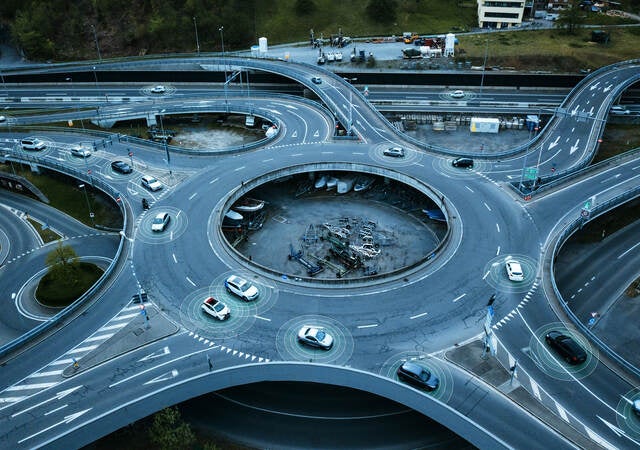 Autonomous self-driving cars moving in a traffic circle next to a highway. 