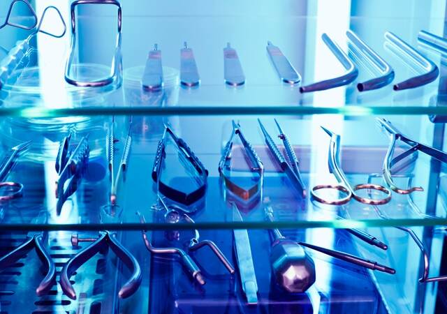 An array of medical devices sit within a cabinet basking in UV light.