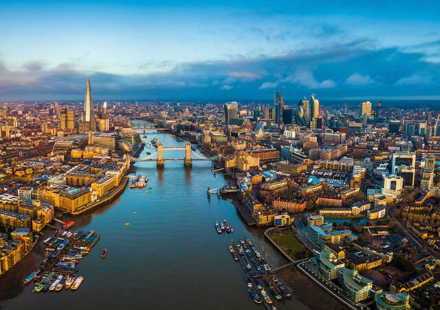 Golden hour aerial view of London’s skyline, including the Tower Bridge and famous skyscrapers.