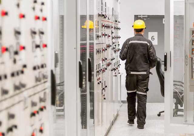 Engineer using protective relay and medium voltage switchgear in a bay control unit.