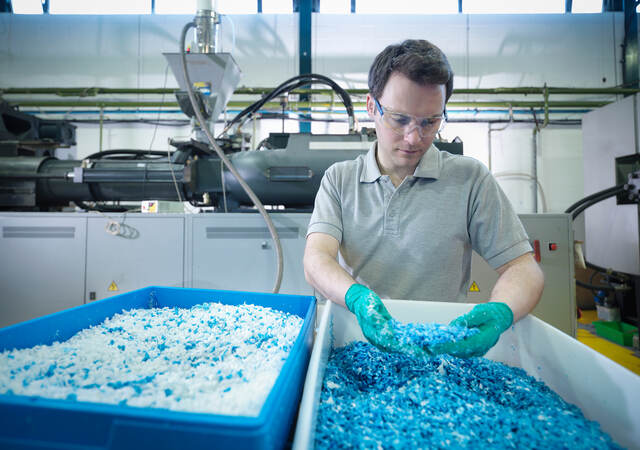 Worker inspecting recycled plastic in plastics factory