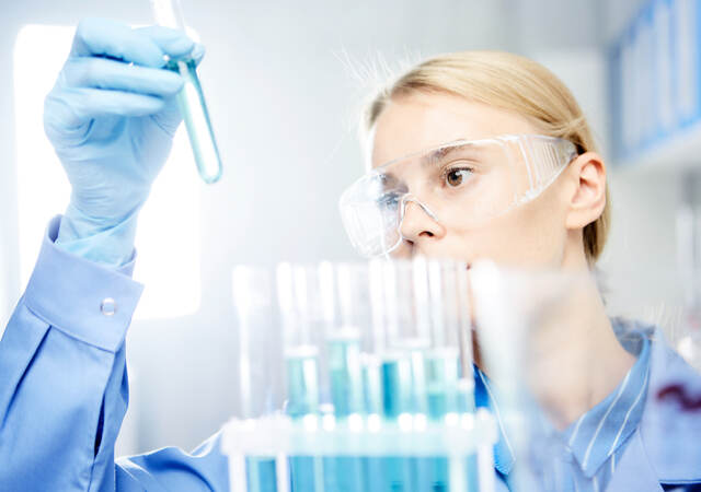 Young woman working in laboratory, handling test tubes