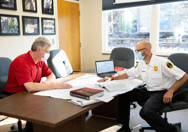 Two code authorities sitting at a table together looking at building plans.