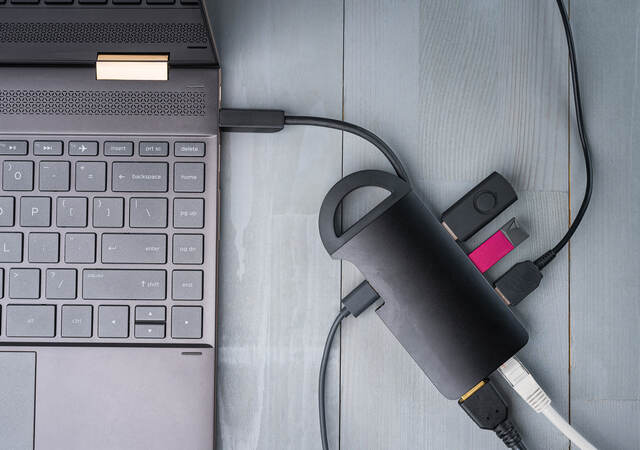 USB Type C adapter or hub connected to the laptop with various accessories – USB drives, HDMI, Ethernet, cables