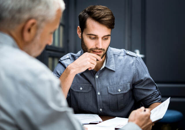 Two male business professionals reviewing documentation at workplace.