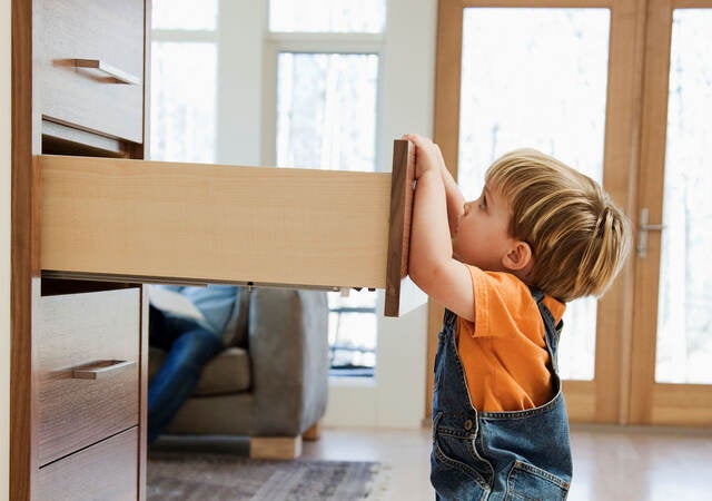 A child pulling on an open dresser drawer, a furniture tip-over risk