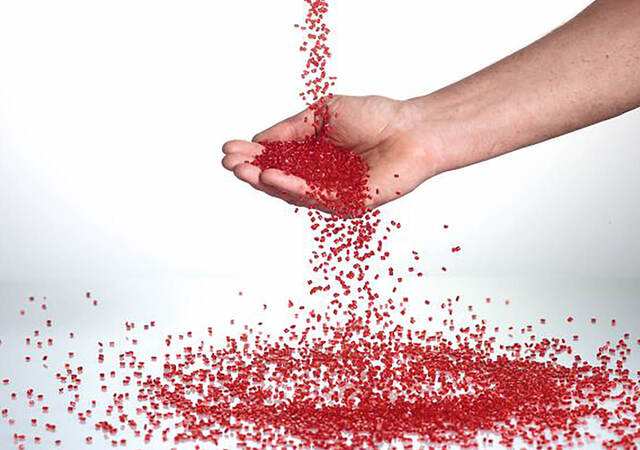 A hand catching red plastic pellets