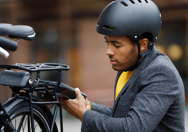 Young man changing battery pack on electric bicycle