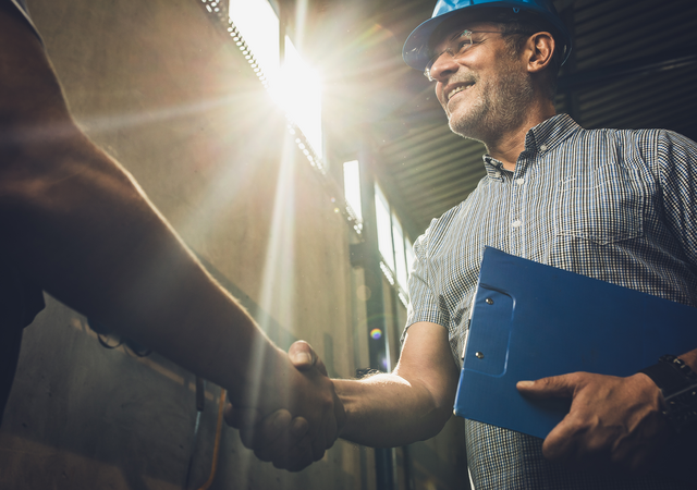 Man in hardhat and clipboard shaking hands