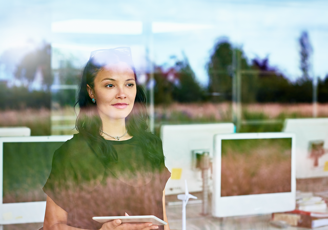 A woman views outside with computers behind her