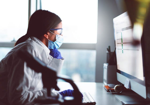 Female engineer with face mask at desk