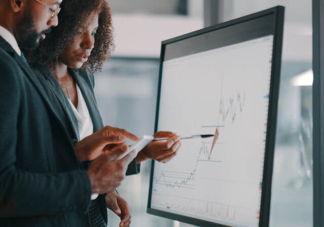 Shot of a young businessman and businesswoman using an interactive whiteboard to analyse data in a modern office