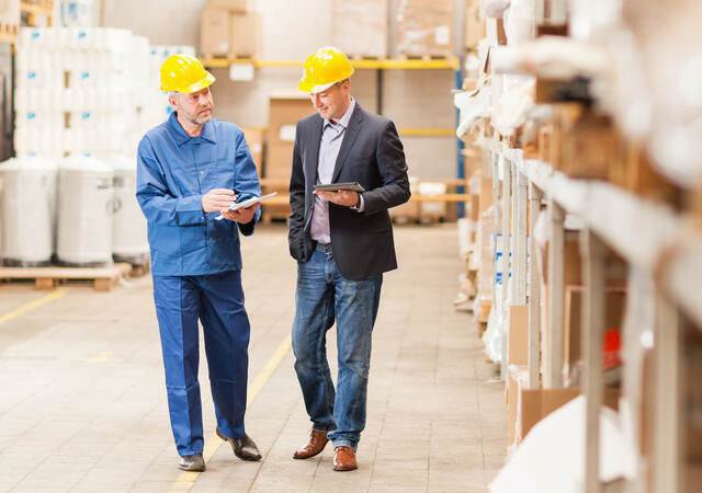 Men wearing hardhats in warehouse talking