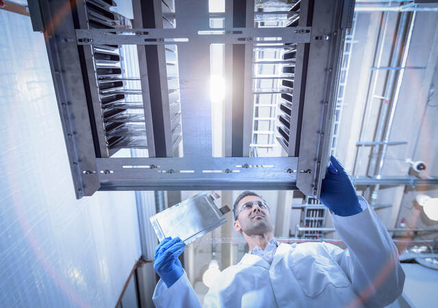 Scientist with lithium ion pouch cell manufacture machine in battery research facility