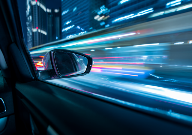 Heavy traffic flows both directions on a busy city highway in between high-rise buildings