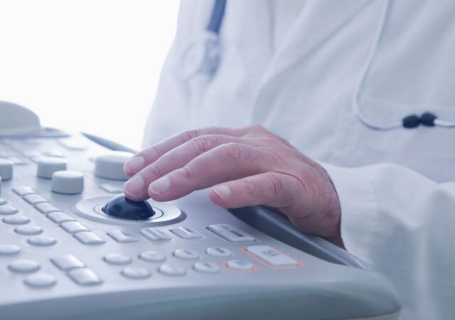 A doctor operates an ultrasound scanner