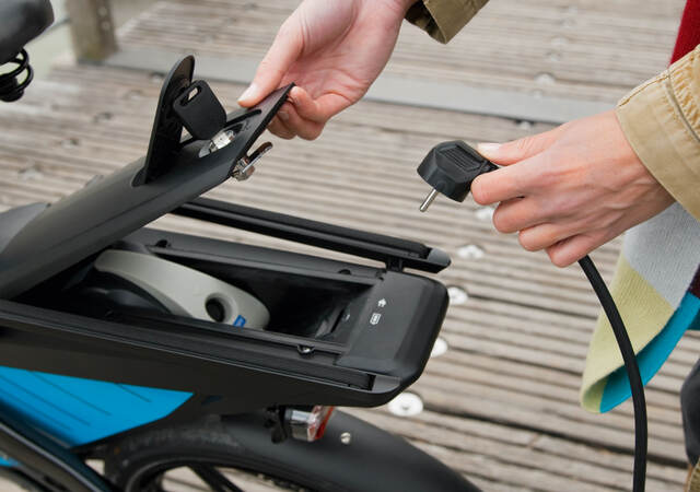 Woman charging electric bike outdoors