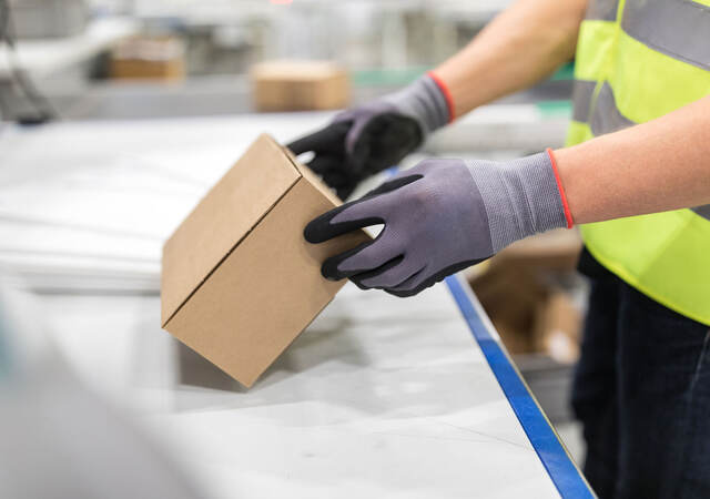 Worker checking package from conveyor belt in warehouse