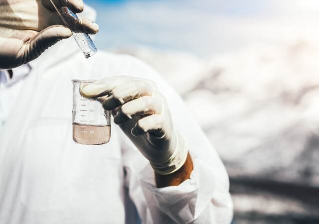 Person in protective suit examining polluted water