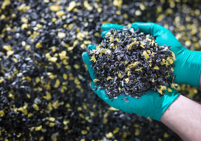 Worker holding recycled plastic in plastics factory