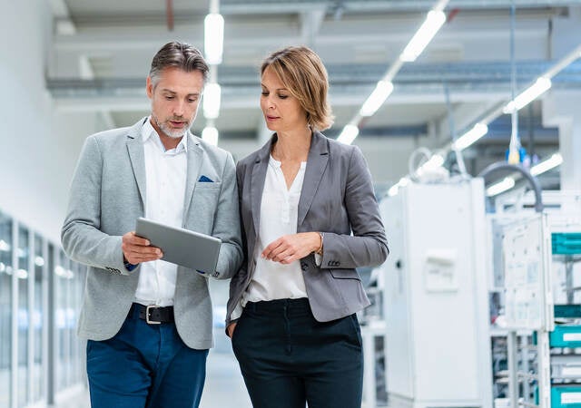 Two workers collaborating on a device while walking