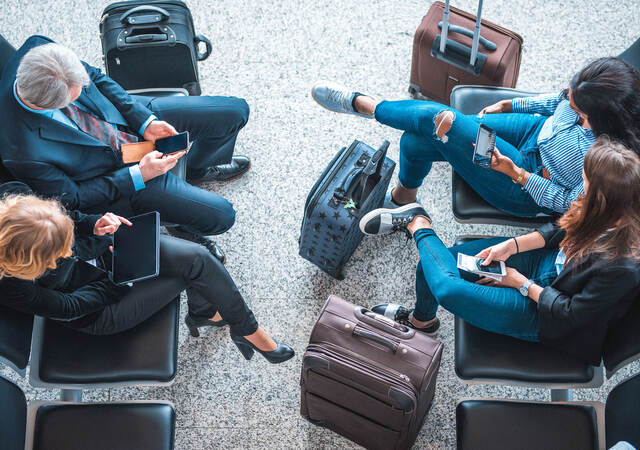 Passengers using mobile devices while waiting at an airport