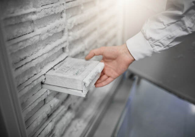 A scientist removing a sample from a laboratory freezer