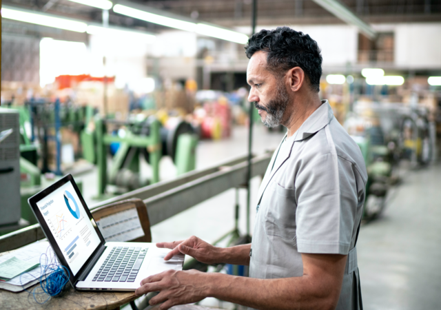 Manufacturer using a laptop on the warehouse floor