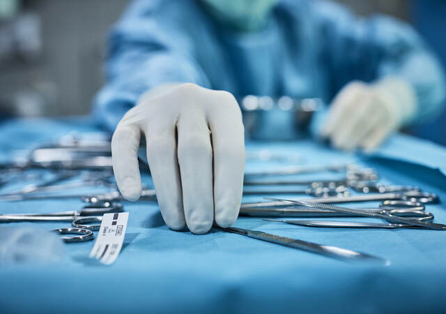 Surgeon picking up surgical tool from tray