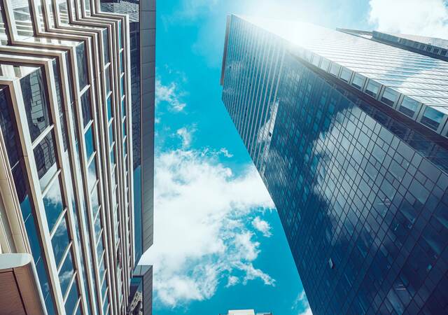 sky with clouds peeking through tall buildings