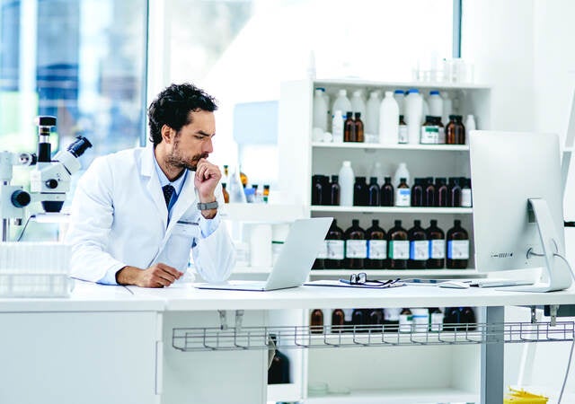 A doctor operates a computer in a laboratory setting.