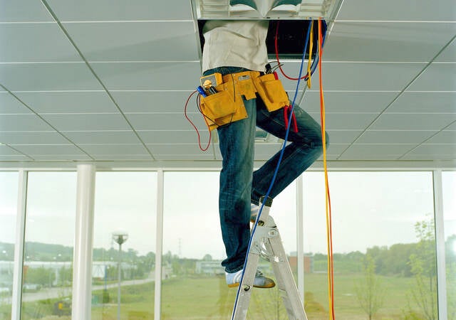 Man on step ladder, working through gap in ceiling, low section