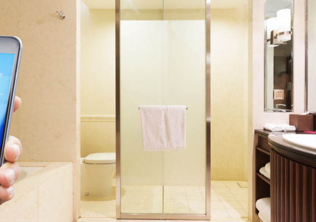 A hand holds a smartphone while in a modern bathroom