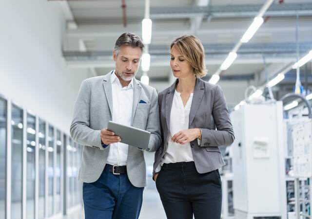 Workmates walking and discussing a subject while looking at a tablet