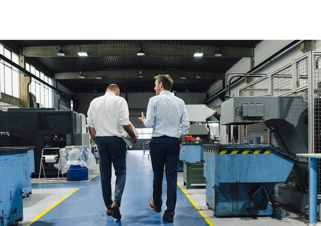 Two men walking and talking in a factory