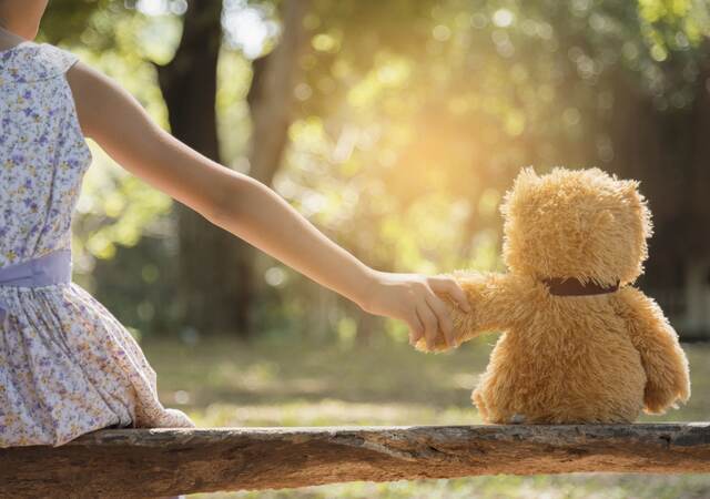 Young girl holding hands with a teddy bear