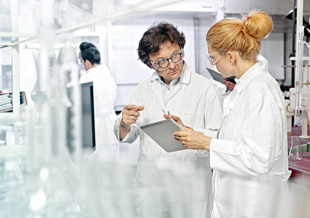 Two scientists working on a tablet in a lab