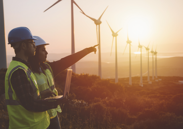 Maintenance engineer team working in wind turbine farm at sunset