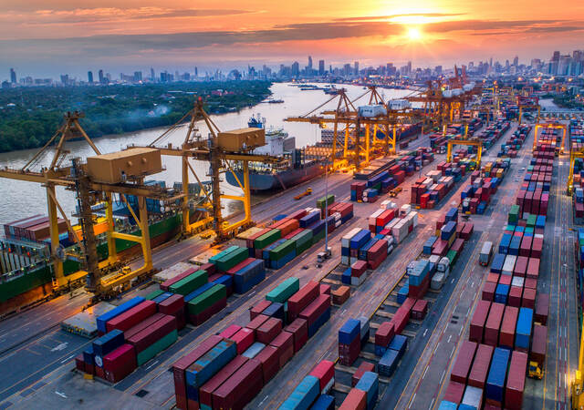 Container cargo ship and cargo plane with working crane bridge in shipyard at sunrise