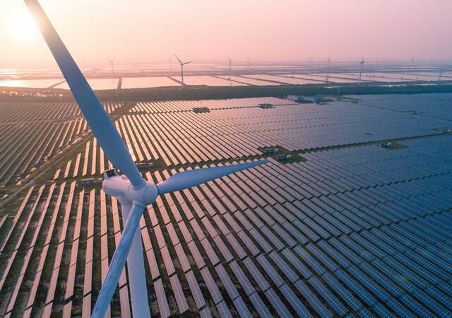 Wind turbines over a solar panel field