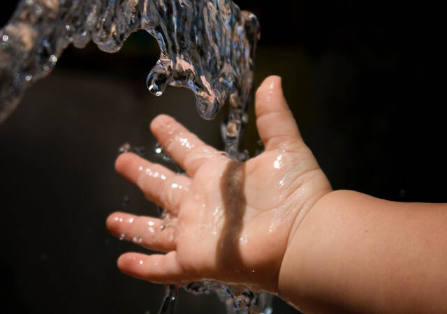 Baby holding hand under running water