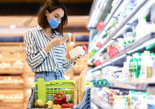 Person in supermarket checking a label on a food product