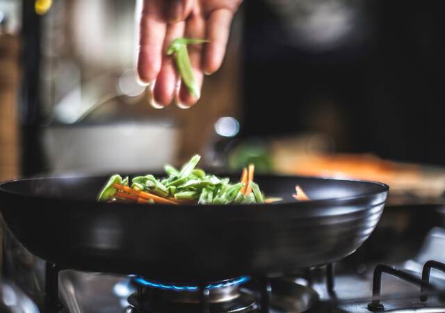 Sprinkling shredded vegetables in a pan for Korean pancakes.