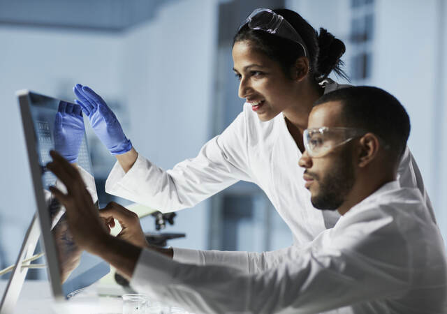 Scientists in laboratory working with computer and microscope