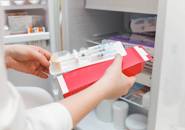 Laboratory technician retrieving refrigerated vaccines